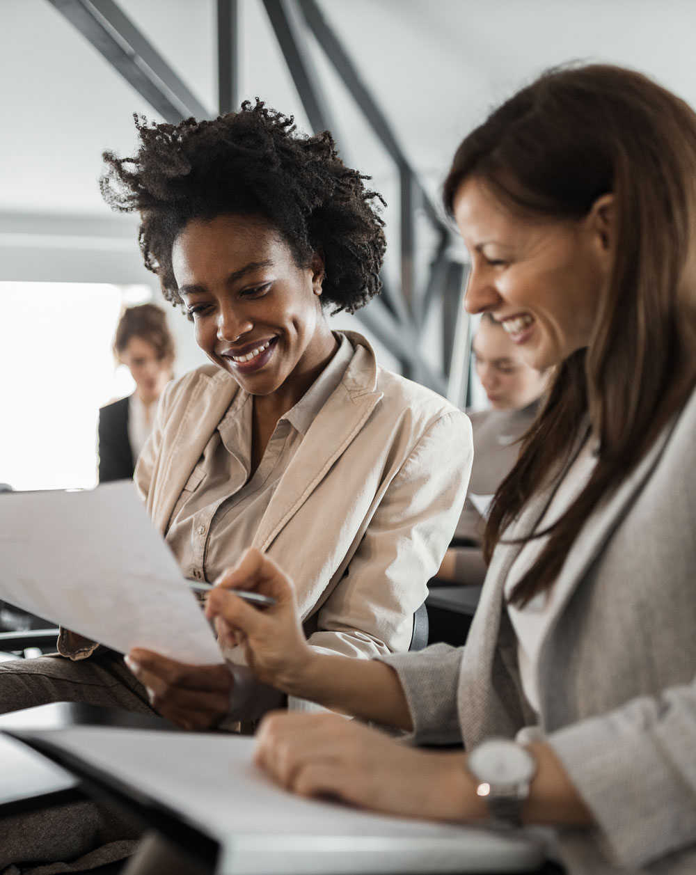 two_female_colleagues_smiling_discussing_a_paper